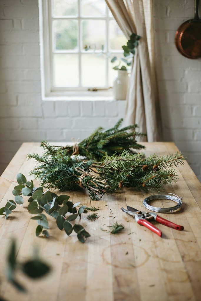 Bundles of fresh cedar, pine, and eucalyptus laid on a wooden cottage table ready for Christmas decorating